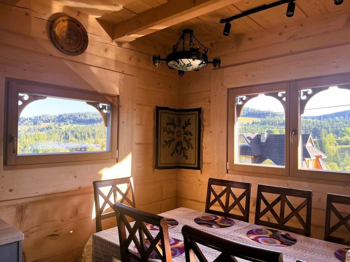 Jadalnia z drewnianymi krzesłami i oknami z widokiem na las