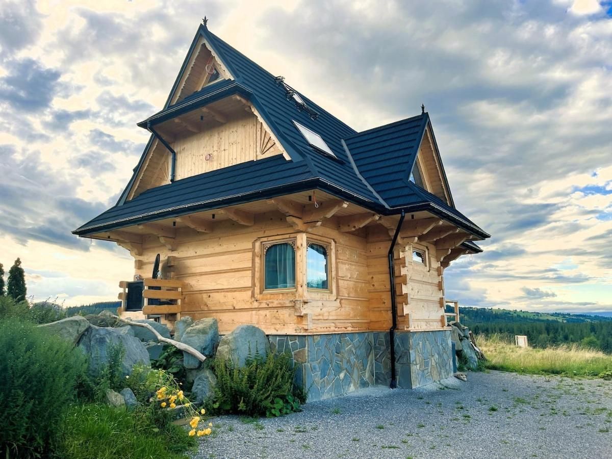 Dom z bali na kamiennej podmurówce pod chmurnym niebem